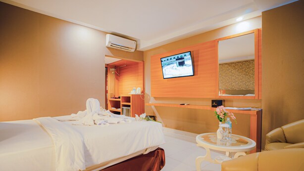 A hotel room with a bed, a TV mounted on the wall, a desk, and a chair. - Portola Arabia Hotel Banda Aceh  (Banda Aceh)