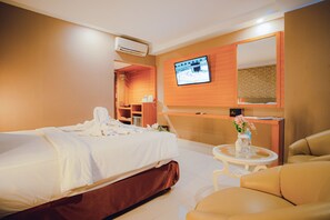 A hotel room with a bed, a TV mounted on the wall, a desk, and a chair. - Portola Arabia Hotel Banda Aceh  (Banda Aceh)