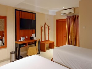 Habitación de hotel con cama, escritorio, silla, televisor y aire acondicionado.