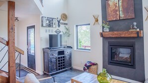 Ein geräumiges Wohnzimmer mit Kamin, einem Wand-Fernseher und einem großen Fenster, das für natürliches Licht sorgt.