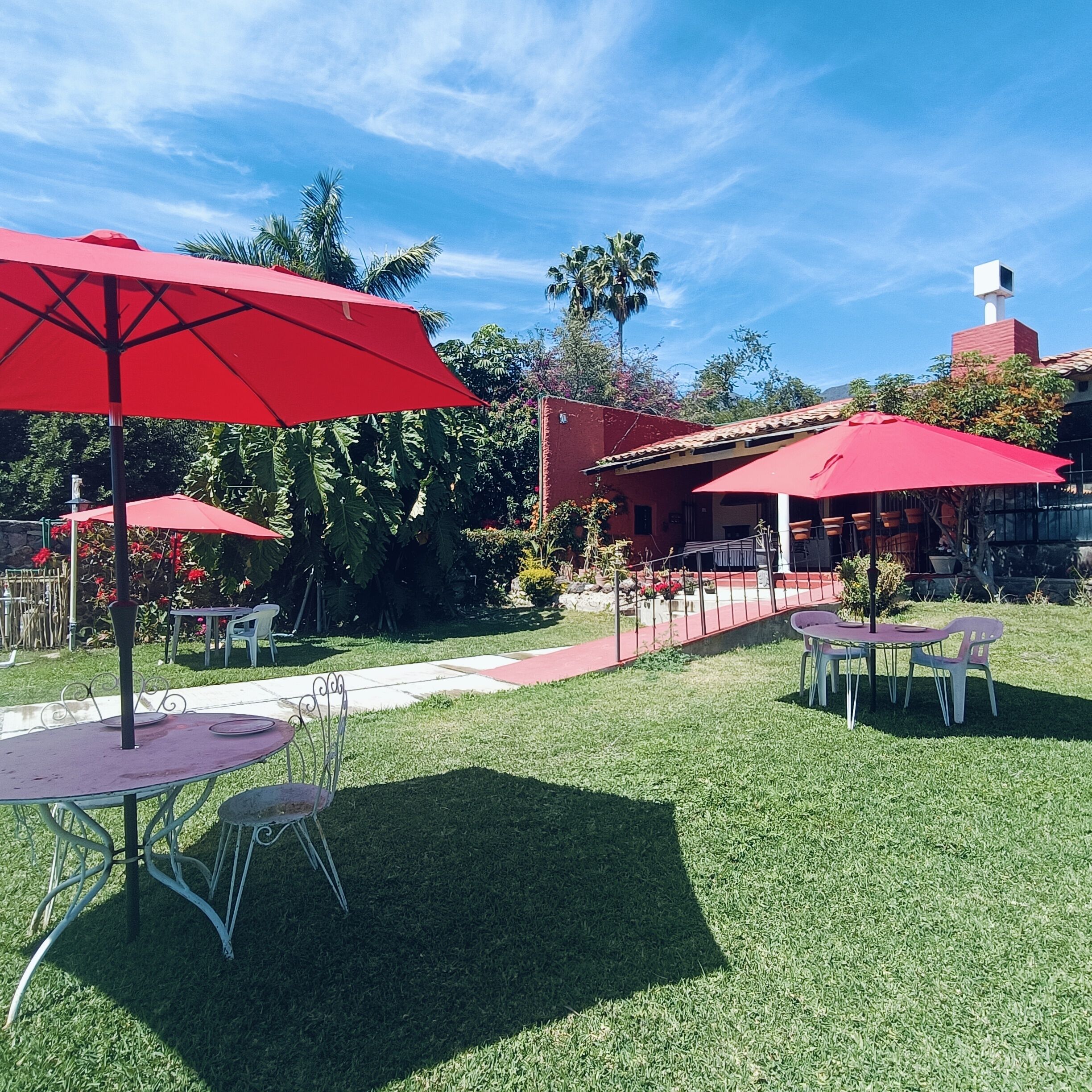 An outdoor patio area with red umbrellas, metal tables, and chairs.