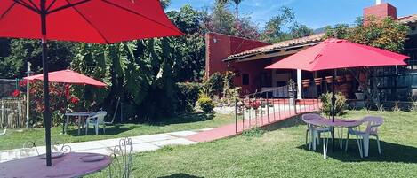 An outdoor patio area with red umbrellas, metal tables, and chairs.