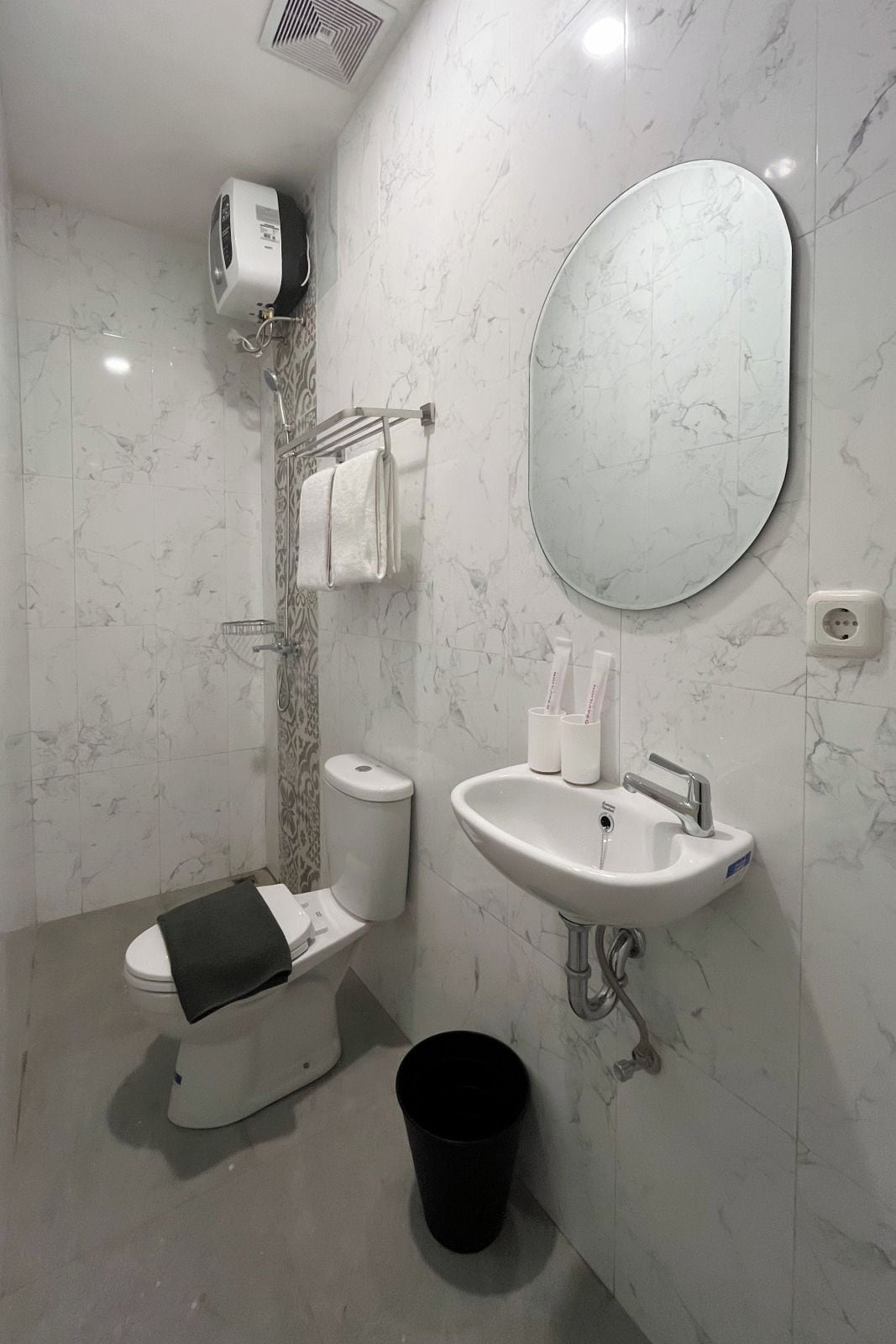 Un baño moderno con inodoro, lavamanos, espejo y zona de ducha.
