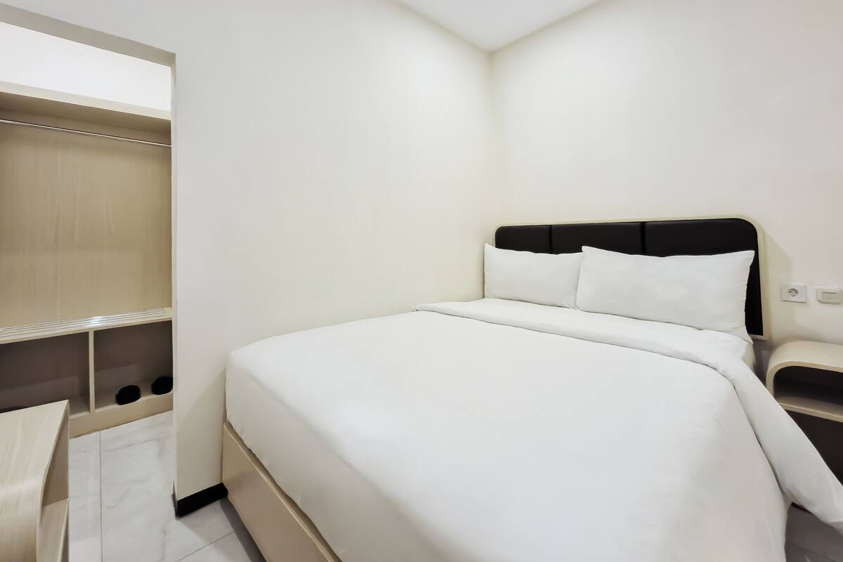 A modern hotel room with a large bed, a bedside table, and a built-in wardrobe.