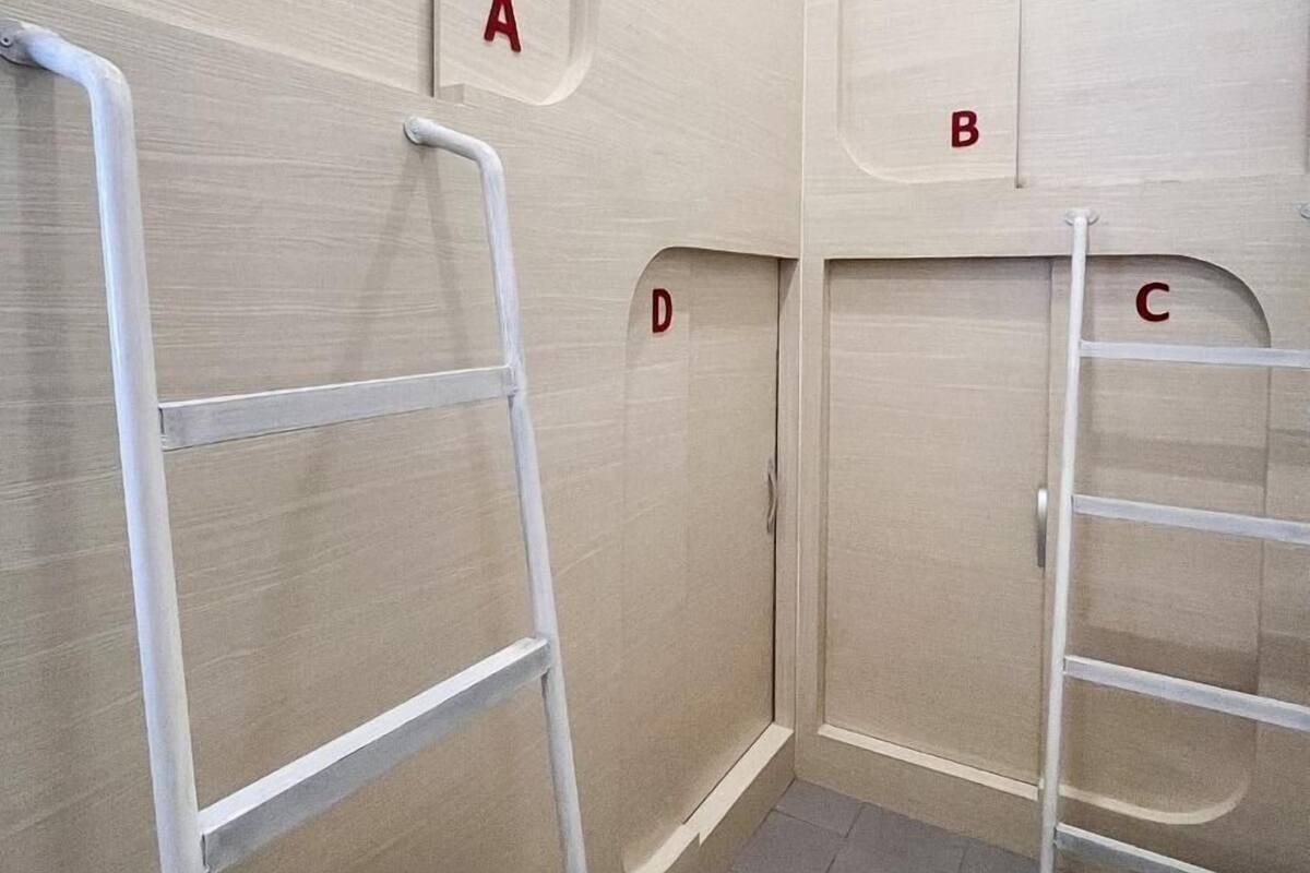 A room with a tiled floor, white walls, and a door labeled 'A'. There are two white metal ladders against the walls.