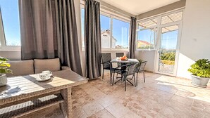 Un balcon ensoleillé avec une table à manger, des chaises et un canapé.