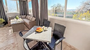 Une pièce lumineuse, avec une table à manger, des chaises, un canapé et une fenêtre avec des rideaux.
