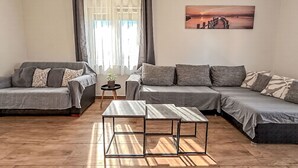 Un salon moderne avec un canapé d’angle, une petite table ronde et un tableau accroché au mur.
