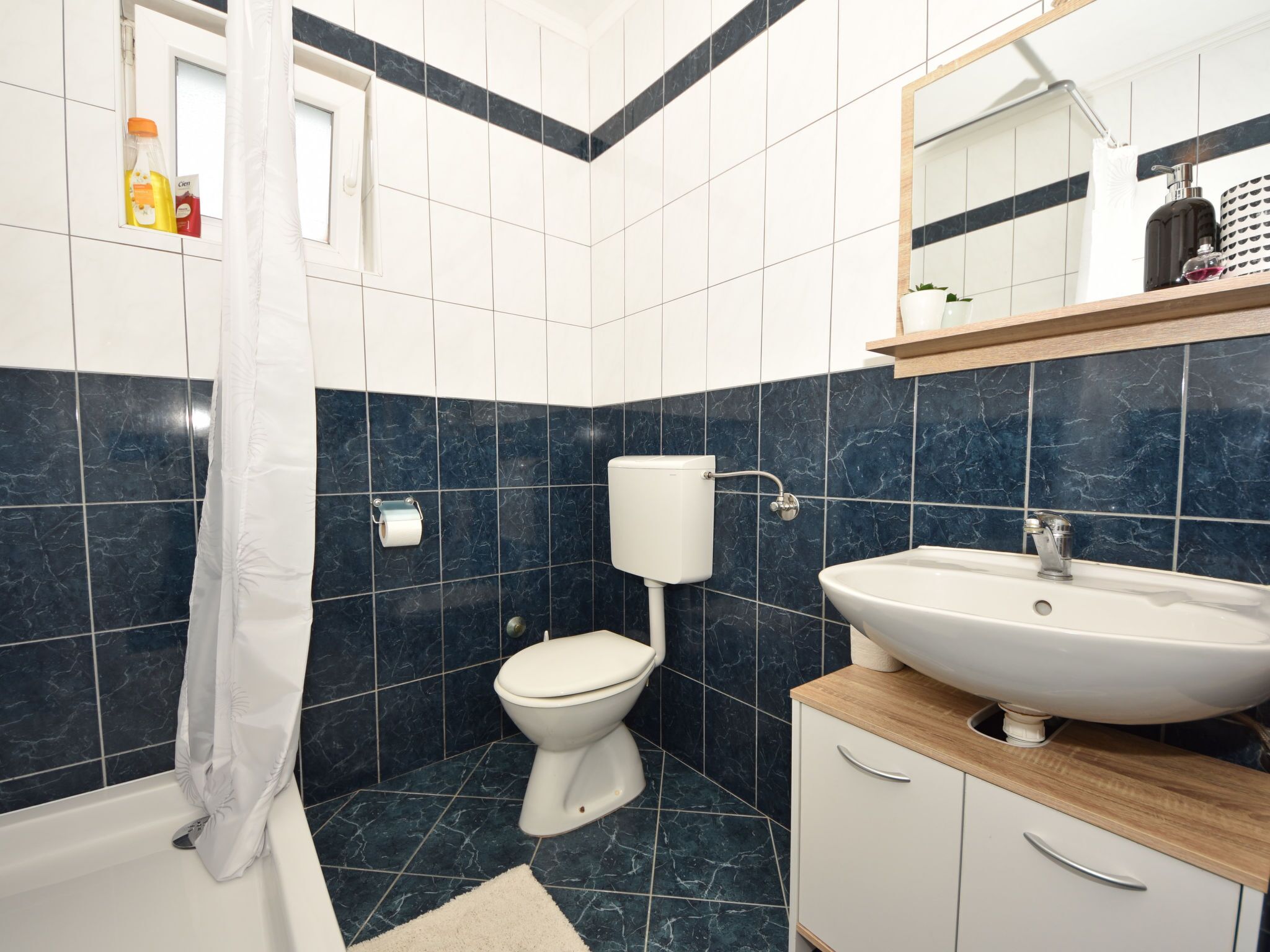 Un baño con inodoro, lavamanos y cortina de ducha.