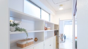 A modern interior with white shelving units, a wooden cabinet, and a potted plant. - Kamata Smile House (Tokyo)