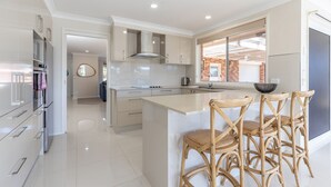 A modern kitchen with a central island, stainless steel appliances, and a view of a brick building through the window. - 114 Elizabeth on the Forster Keys (Forster)