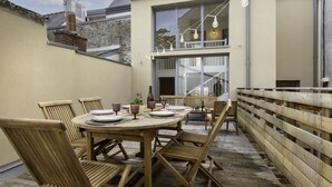 A wooden deck with a round table set for dining, surrounded by wooden chairs. - L'Oiseau 1 by Interhome (Dinard)