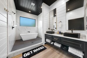 Une salle de bain moderne avec une baignoire sur pieds, deux vasques et un grand miroir.