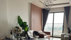 Un salon moderne avec un plancher en bois, un canapé, une table basse et une grande fenêtre avec des rideaux.