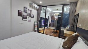 Une chambre d’hôtel moderne dotée d’un grand lit, d’un téléviseur à écran plat et offrant une vue sur la ville grâce à une porte vitrée.