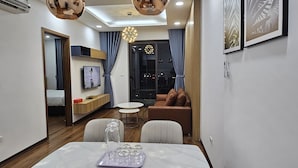 Un salon moderne avec un coin repas, comprenant une table en marbre, un canapé et un téléviseur fixé au mur.