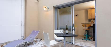 Eine Terrasse mit Tisch, zwei Stühlen und einer Weinflasche.