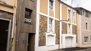 Une rangée d’immeubles résidentiels aux façades en pierre et en bois, avec des fenêtres blanches et une porte de garage.