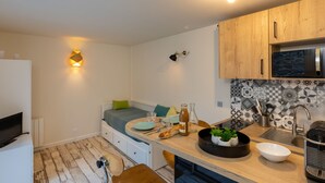 Une cuisine compacte dotée de meubles en bois, d’un four à micro-ondes, d’un évier et d’un coin repas avec un banc.