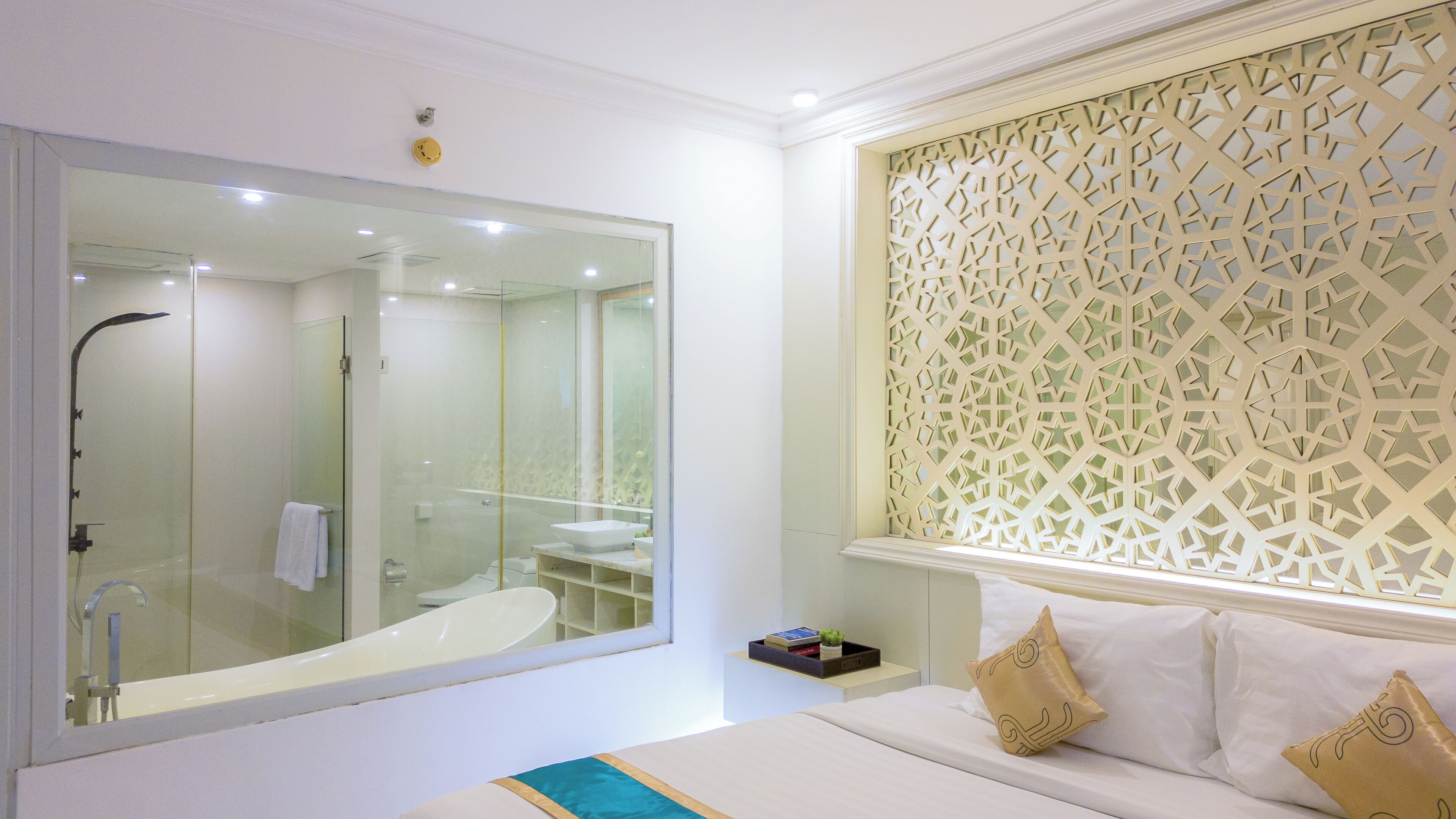 Un baño moderno con un espejo grande, cabina de ducha con mampara de cristal y una celosía decorativa en la ventana.