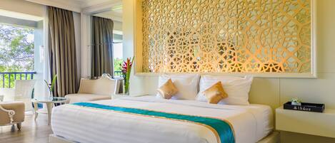 Amplia habitación de hotel con una cama grande, un rincón de descanso con una mesa y sillas, y un panel decorativo en la pared.