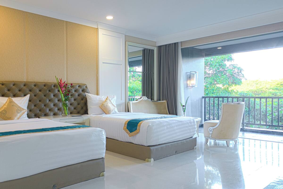 Une chambre d’hôtel avec deux lits, un balcon et une vue sur la verdure.