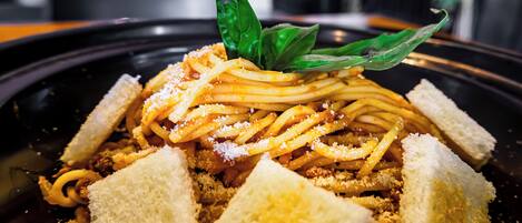 A plate of spaghetti with bread and a basil leaf garnish.
