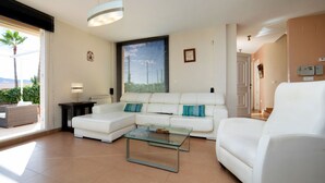 A modern living room with a white sofa, a glass coffee table, and a large window with blinds. - Casa Viena by Interhome (Albir)