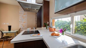 A modern kitchen with a central island, stainless steel sink, and a window with a view of greenery. - Casa Viena by Interhome (Albir)