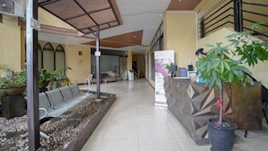 A reception area with a counter, seating, and potted plants. - Arzo Hotel Grand Lodge (Manila)