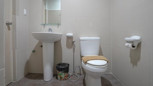 A bathroom with a white sink, toilet, and a glass shelf above the sink. - Arzo Hotel Grand Lodge (Manila)