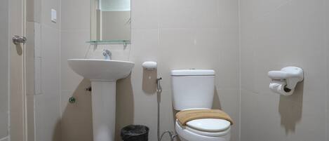 Un baño con un lavabo blanco, inodoro y un estante de vidrio sobre el lavabo.
