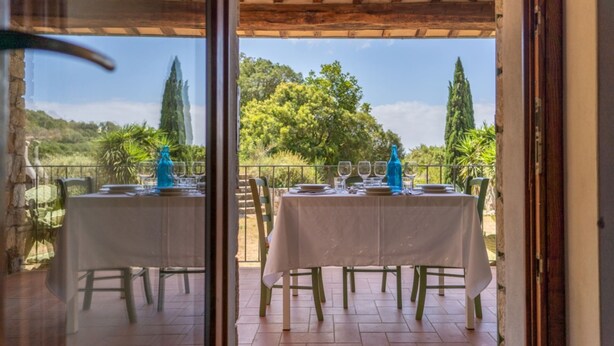 Un área de comedor al aire libre con mesas dispuestas para dos, con vistas a un paisaje pintoresco.