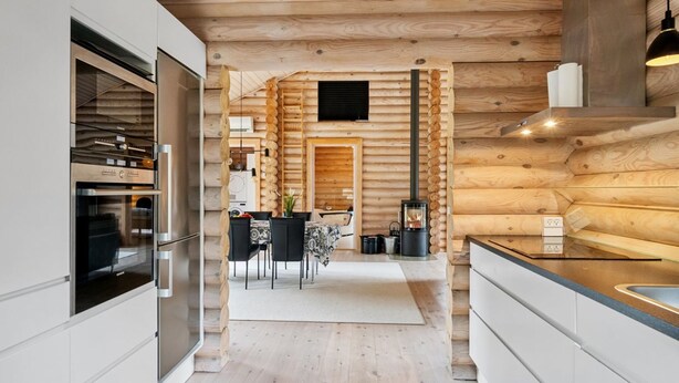 A modern kitchen with wooden walls, a built-in oven, and a dining area with a table and chairs.