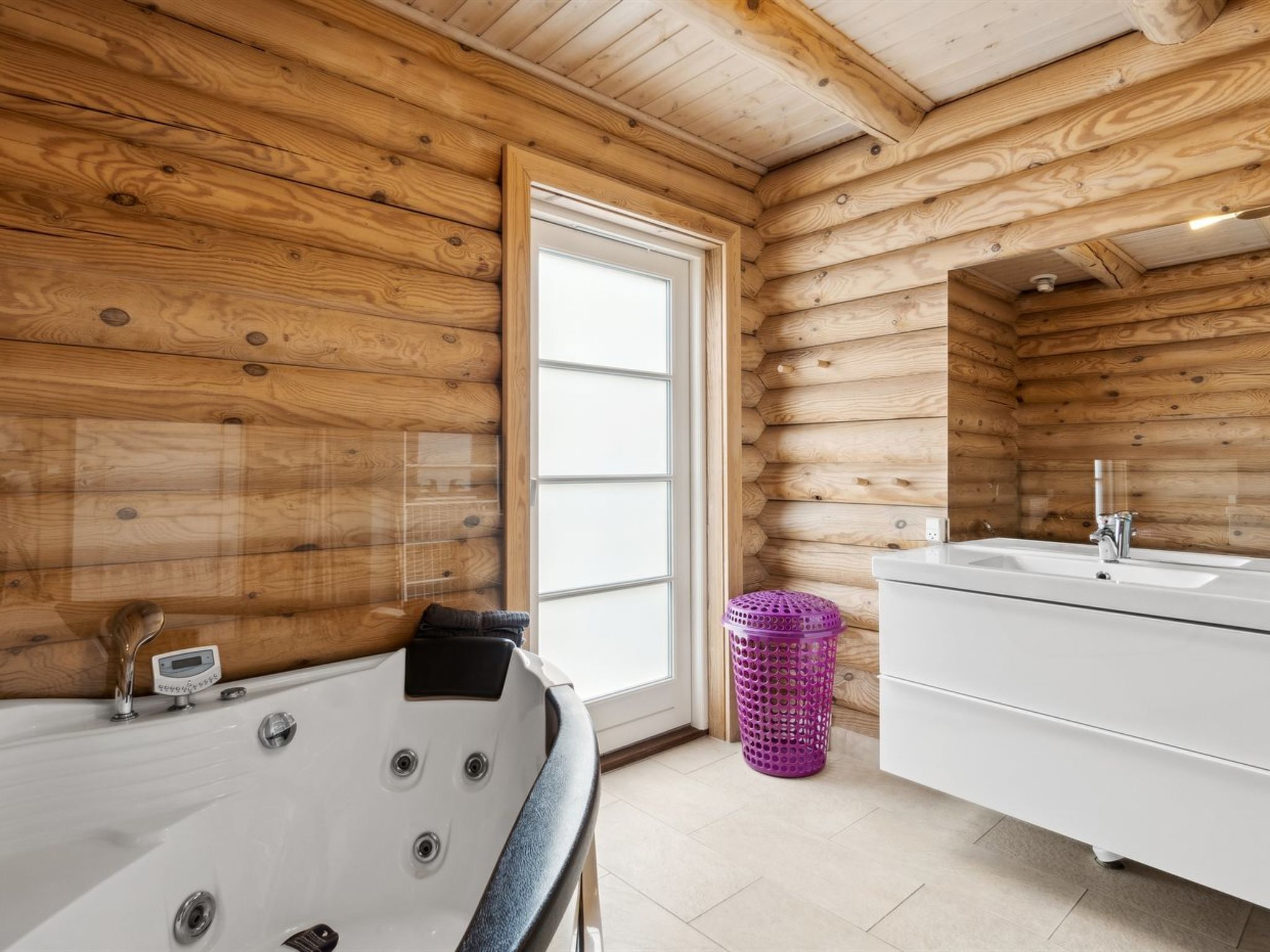 Bagno di una casetta in legno con una vasca, un lavandino e una finestra.