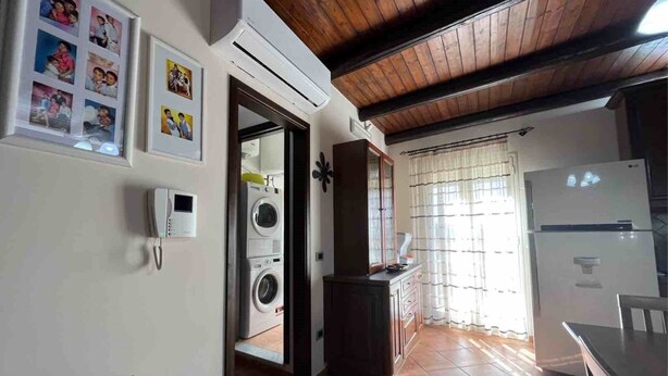 A kitchen with a built-in washing machine, a refrigerator, and a wooden ceiling. - CASA VACANZE PERLA - 6 POSTI LETTO (PARTINICO)