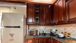 A kitchen with wooden cabinets, a refrigerator, a microwave, a toaster, and a coffee maker. - CASA VACANZE PERLA - 6 POSTI LETTO (PARTINICO)