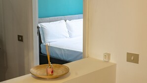A room with a window overlooking a bed, a small table with a candle, and a green upholstered chair. - Domus Otto - Large apartment close to Vatican Museums (Roma)