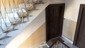 A staircase with a wooden handrail and a dark wooden door at the bottom. - Domus Otto - Large apartment close to Vatican Museums (Roma)