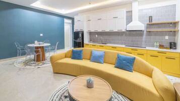 Un salon moderne avec un canapé jaune, une table basse ronde et un coin repas comprenant une petite table et des chaises.