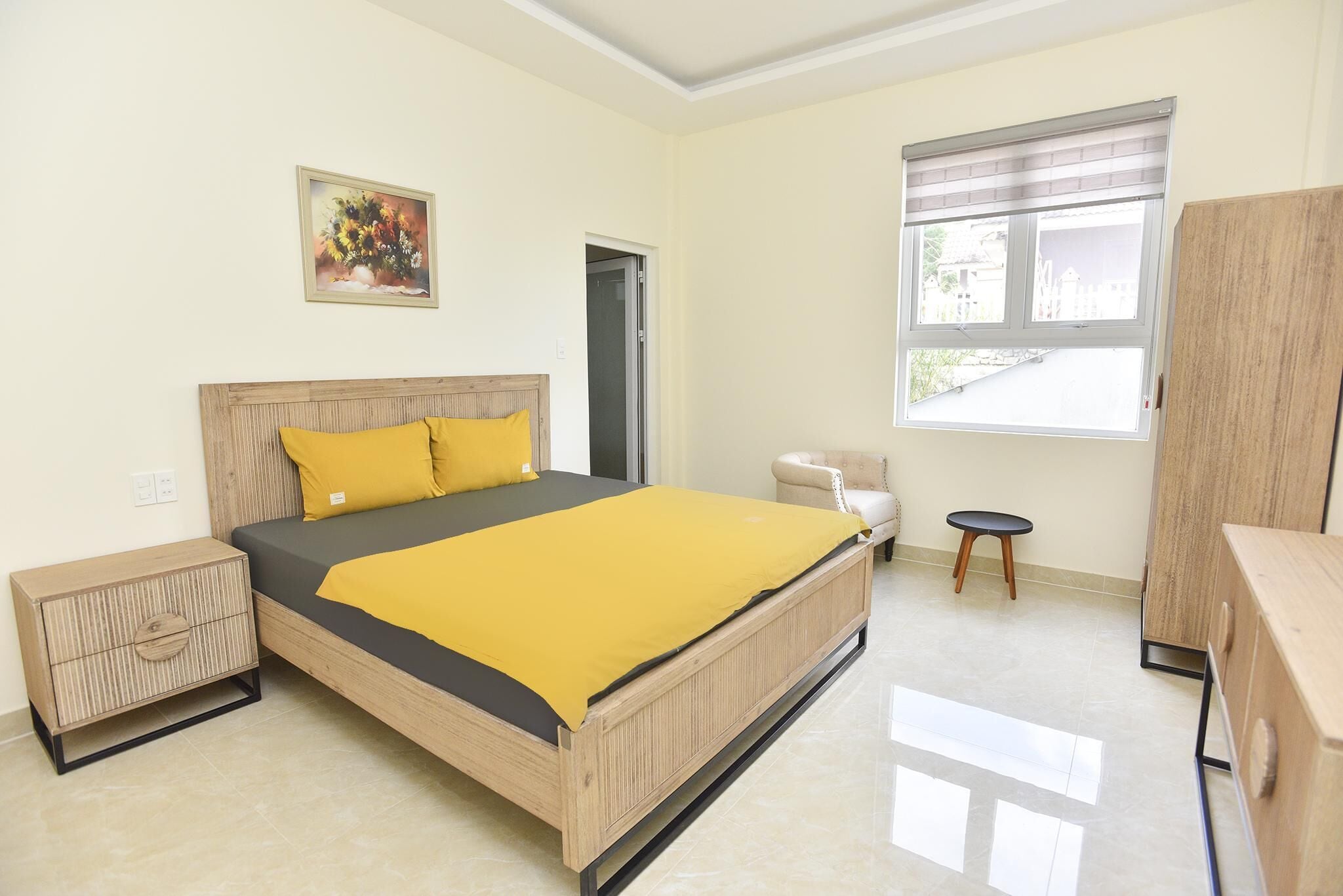A bedroom with a bed, bedside table, wardrobe, window, and a door.