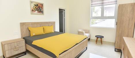 A bedroom with a bed, bedside table, wardrobe, window, and a door.