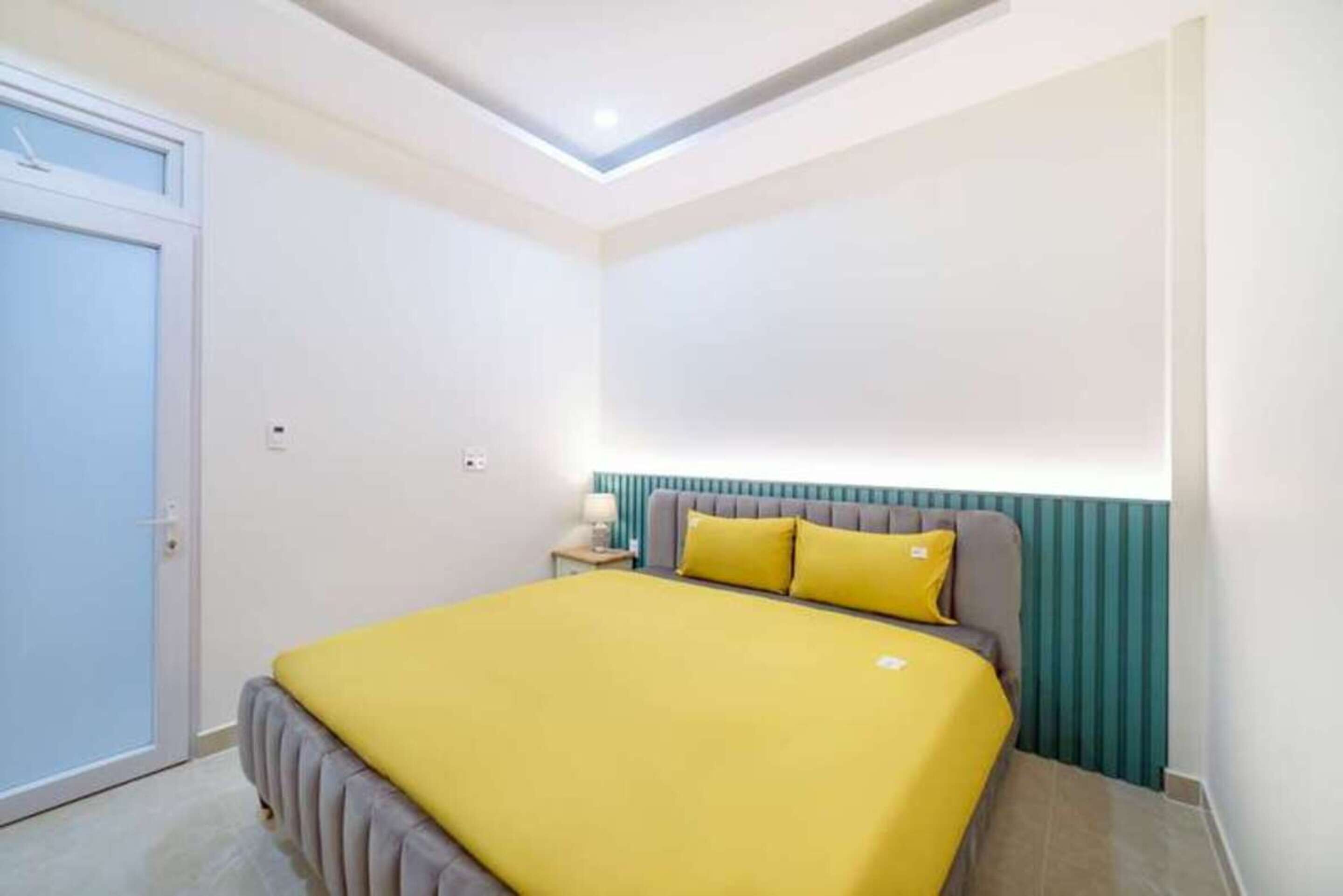Ein Schlafzimmer mit Bett, Nachttisch, Lampe und Tür.