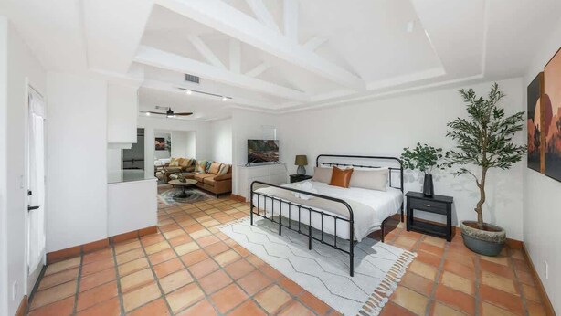 A bedroom with a bed, bedside table, lamp, and potted plant.