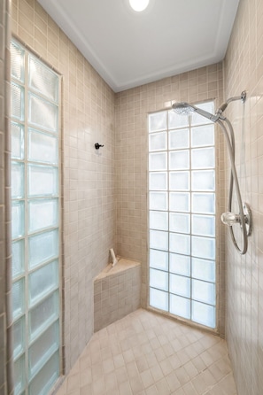 A small, tiled bathroom with a shower, a bench, and a frosted glass window. - Blue Coyote Main -Clean Firepit Spacious Sunset (Yucca Valley)