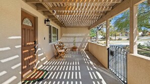 A covered porch with a wooden ceiling, a door, and a small table with chairs.