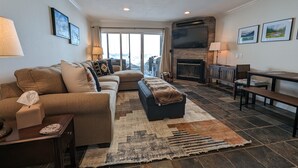A modern living room with a sofa, ottoman, and a fireplace.
