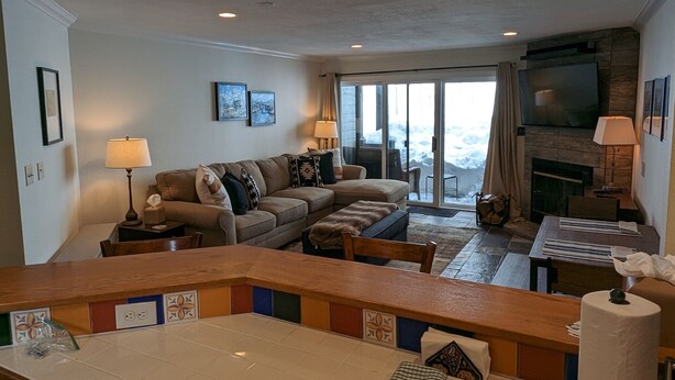 A living room with a sofa, a fireplace, a television, and a view of the outdoors.