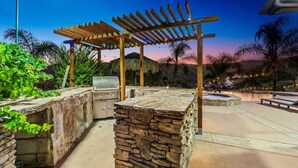 Eine Außenpatio-Terrasse mit Steingrillstation, Holz-Pergola und Sitzgelegenheiten.