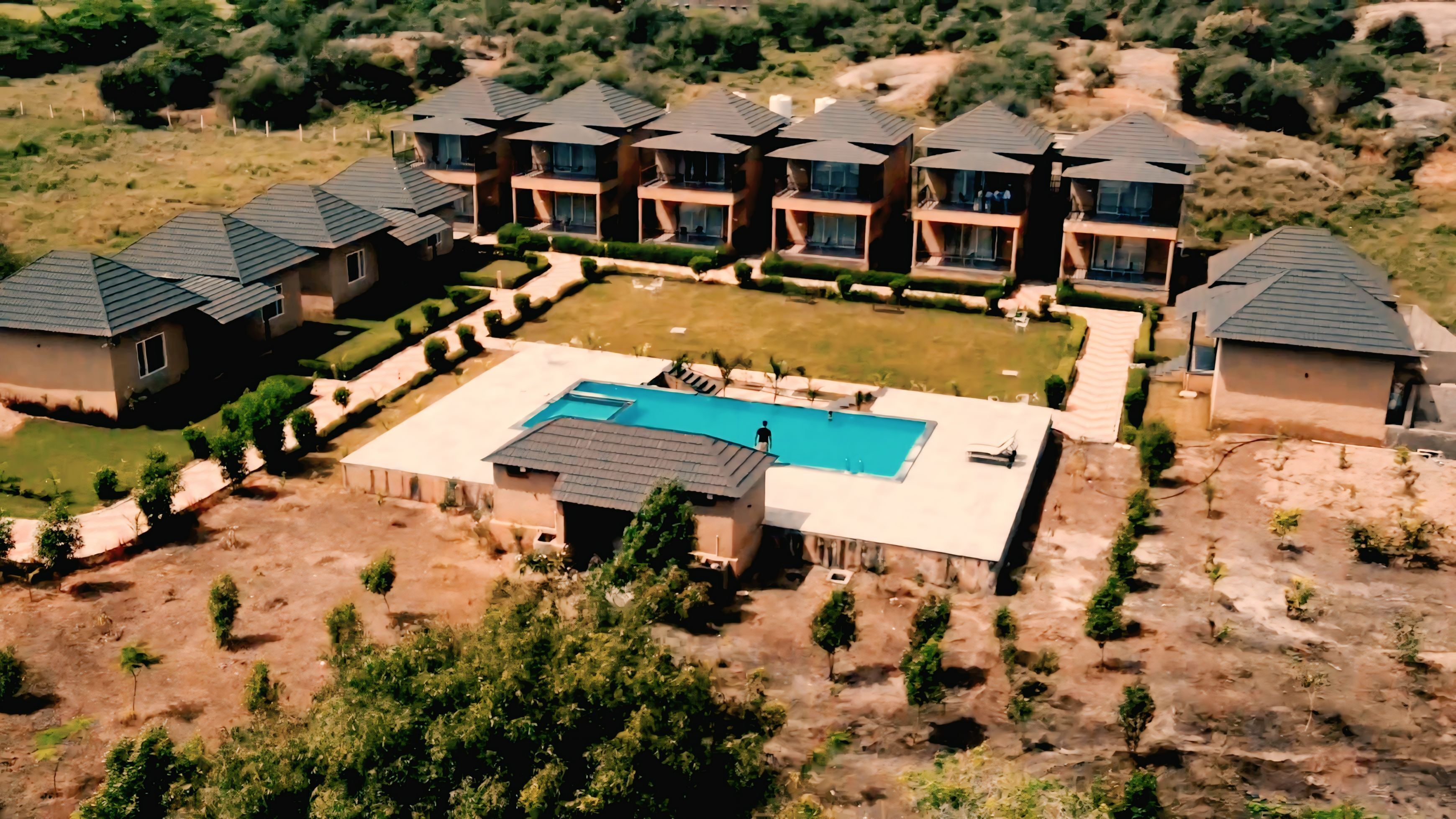 A residential area with multiple houses, a swimming pool, and well-maintained lawns.